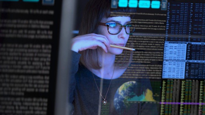 Une personne analysant de grandes quantités de données sur un tableau de bord numérique avec un regard curieux.