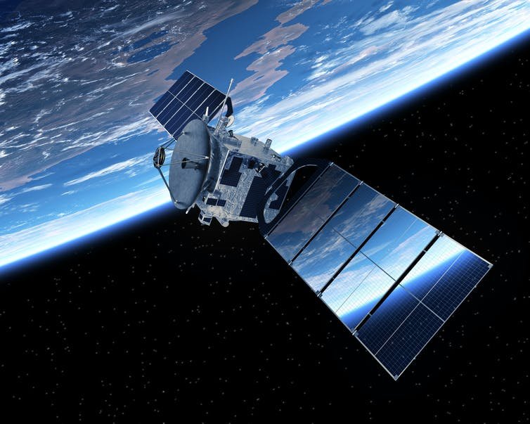 Un satellite dans l'espace orbite autour de la Terre (visible en arrière-plan)