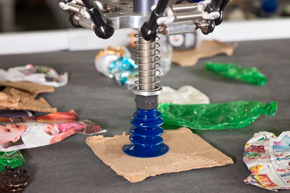 A photo of a robotic gripper on a piece of cardboard.