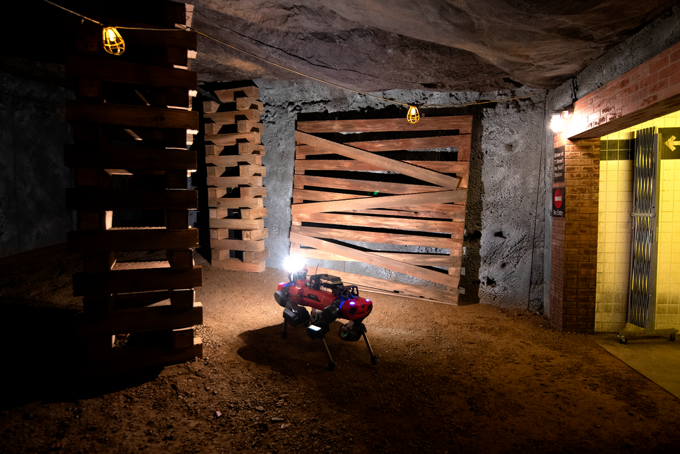 A photo of a quadruped moving through an underground tunnel with wood on the wall.