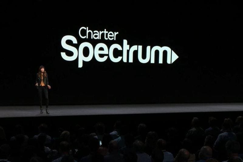 Une femme se tient sur la scène de la WWDC avec le logo de Charter Spectrum derrière elle
