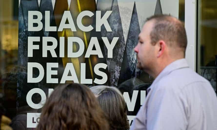 Les gens debout devant un Black Friday deals signe sur une vitrine.