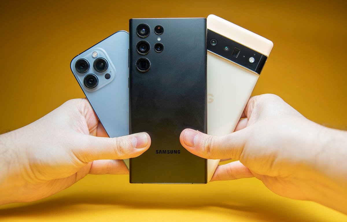 Comment l'appareil photo iPhone 14 d'Apple peut être le meilleur 2 mains tenant le Galaxy S22 Ultra, l'iPhone 13 et le Pro Pixel 6 avec les caméras face au spectateur