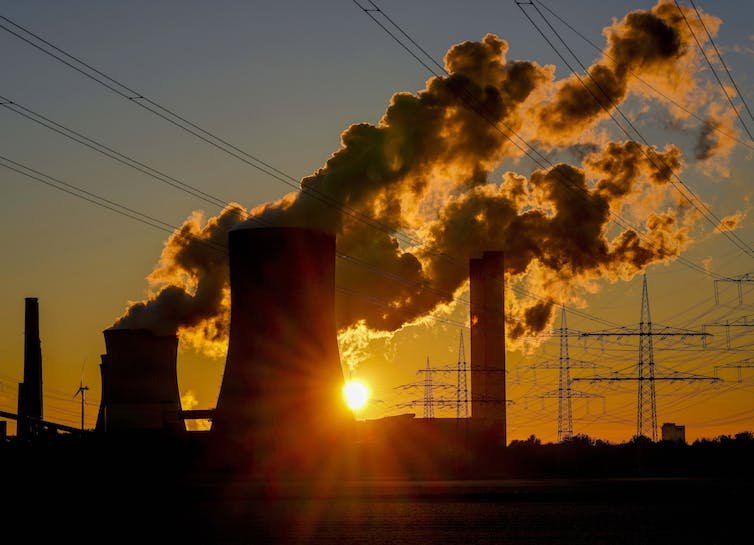 soleil se couche derrière la centrale émettant de la vapeur