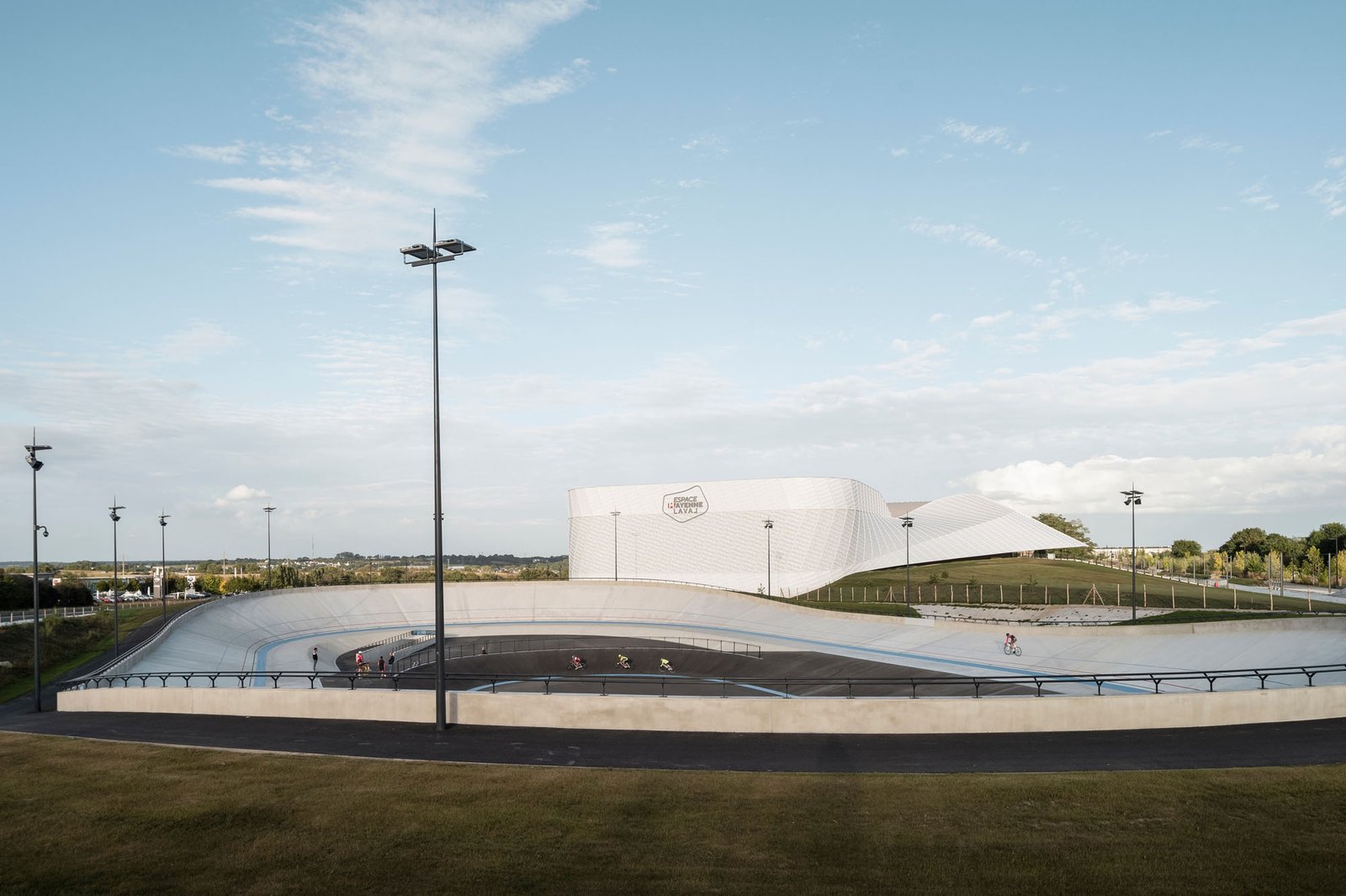 extérieur du centre sportif de l'espace mayenne blanc avec une forme géométrique plongeante et une piste cyclable devant 