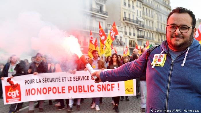 Un homme tient une fusée éclairante devant une banderole syndicale CGT Un homme tient une fusée éclairante devant une banderole syndicale CGT