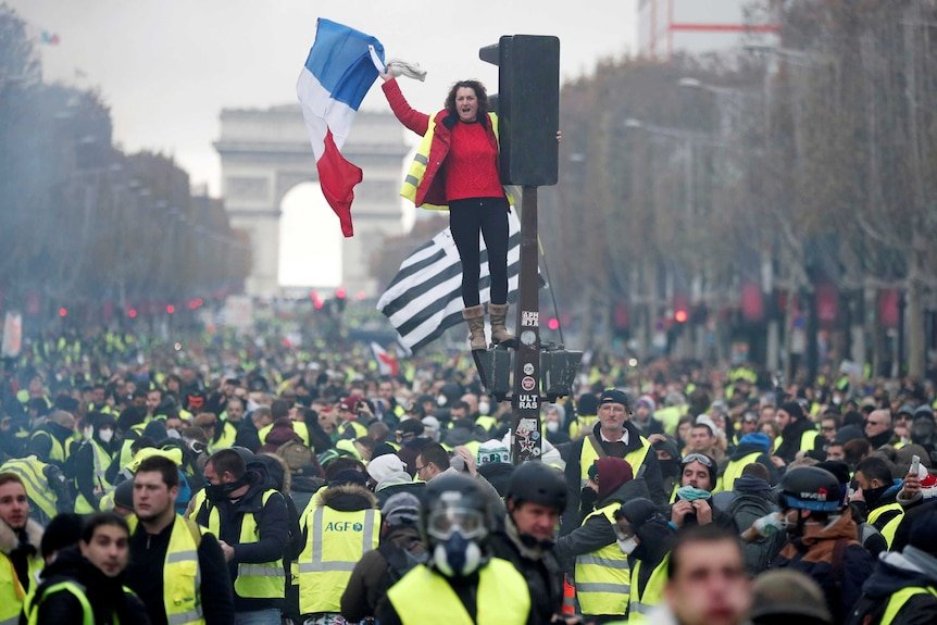 Un manifestant portant un gilet jaune se tient au feu rouge sur les Champs-Elysées à Paris.