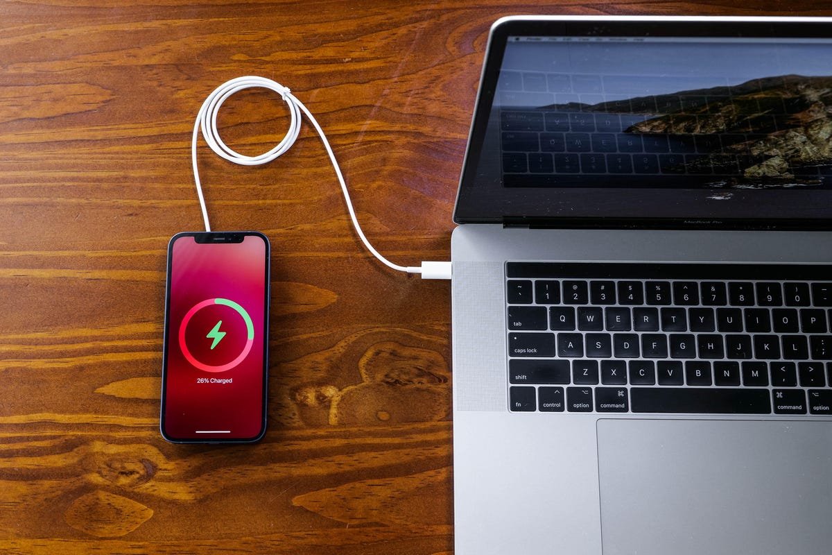 Oubliez USB-C. Un iPhone sans port de charge n'est pas si absurde 4 iPhone connecté à un chargeur MagSafe branché sur un MacBook