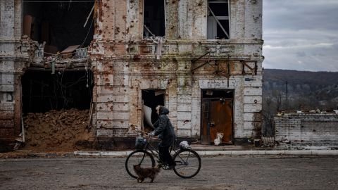 Une femme passe à vélo devant un bâtiment endommagé dans la ville de Kupiansk le 3 novembre 2022, dans la région de Kharkiv, au milieu de l'invasion russe de l'Ukraine.