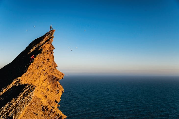 Deux alpinistes sur une falaise en bord de mer en Europe.