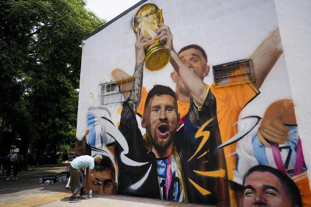Un artiste peint une fresque représentant la star argentine Lionel Messi brandissant le trophée de la Coupe du monde à Buenos Aires, Argentine, le 22 décembre 2022. /CFP
