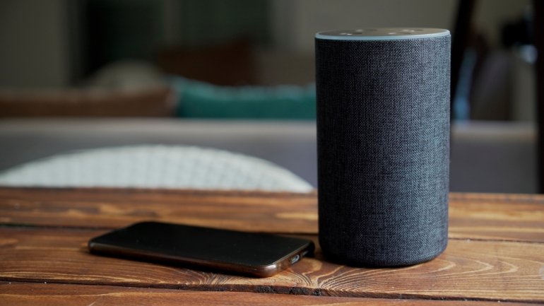 Gris foncé Noir Amazon Alexa Echo et téléphone intelligent sur la table en bois dans un salon.