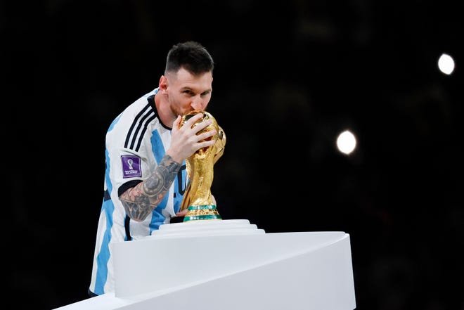 L'attaquant argentin Lionel Messi embrasse le trophée de la Coupe du monde après avoir remporté la finale de la Coupe du monde 2022 contre la France au stade Lusail.