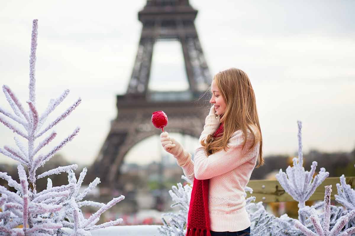 what to wear in winter in paris girl with caramel apple in Paris near the Eiffel Tower.