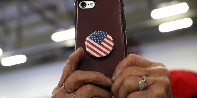 Accessoires iPhone : Voici 5 des meilleurs pour 2023 2 Une femme tient un téléphone orné d'un PopSocket Stars and Stripes.