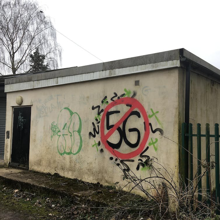 Un graffiti anti-5G sur un mur extérieur en contexte urbain.