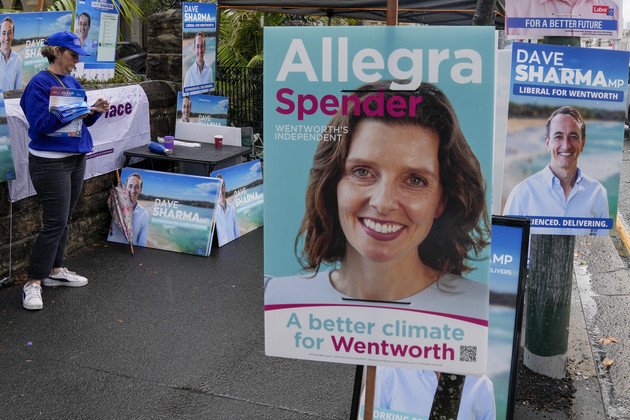 Un bénévole se tient parmi les panneaux d'affichage de la candidate indépendante Allegra Spender et du candidat libéral sortant Dave Sharma devant un isoloir à Sydney, en Australie.