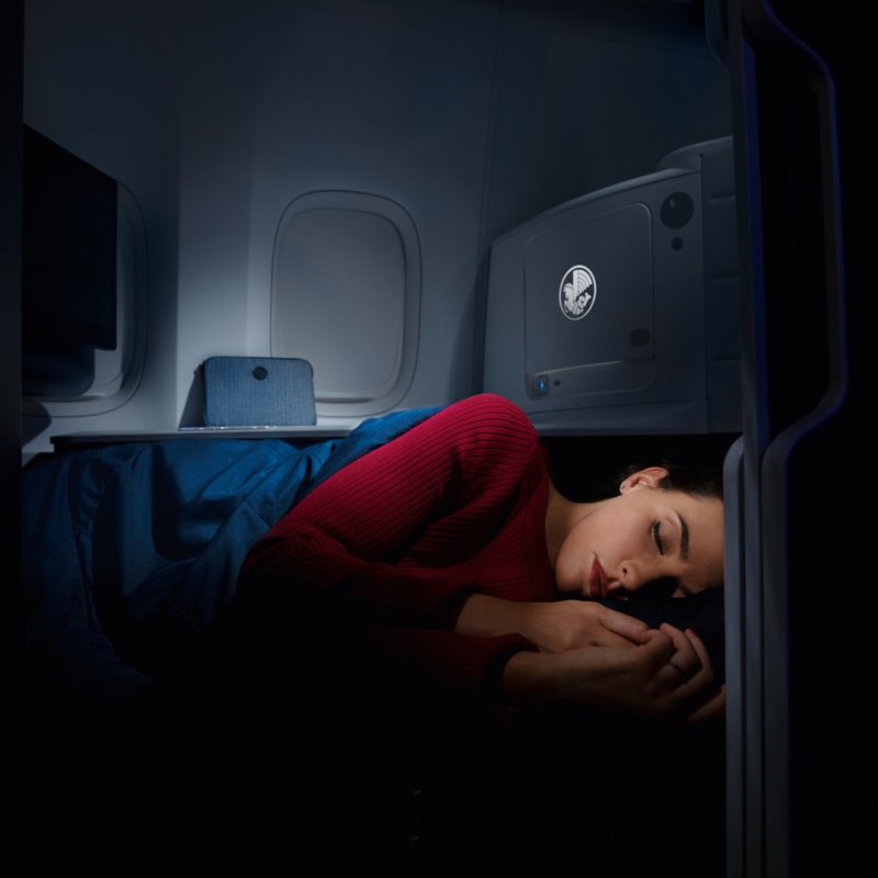 Une femme dort dans une cabine sombre en classe affaires Air France