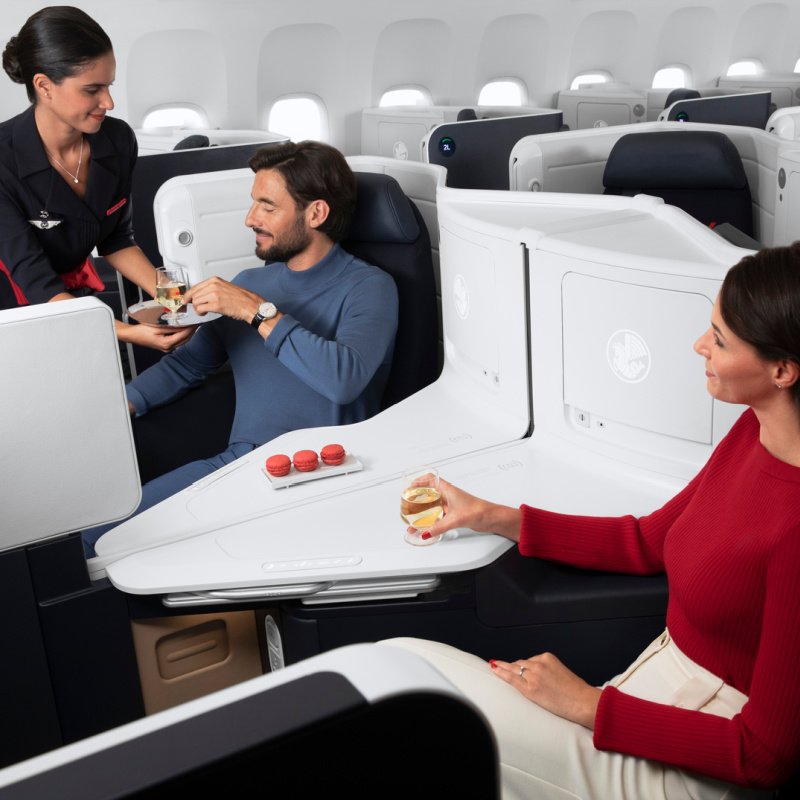 Une hôtesse de l'air livre une boisson à un passager en classe affaires