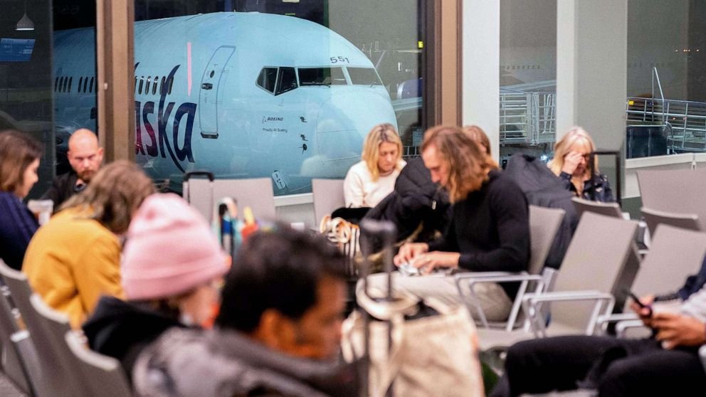 PHOTO : Des voyageurs attendent dans le terminal alors qu'un avion d'Alaska Airlines est assis à une porte de l'aéroport international de Los Angeles à Los Angeles, le 11 janvier 2023.