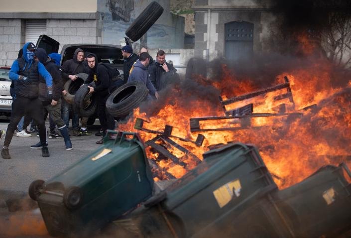 Un manifestant jette des pneus sur un feu de joie