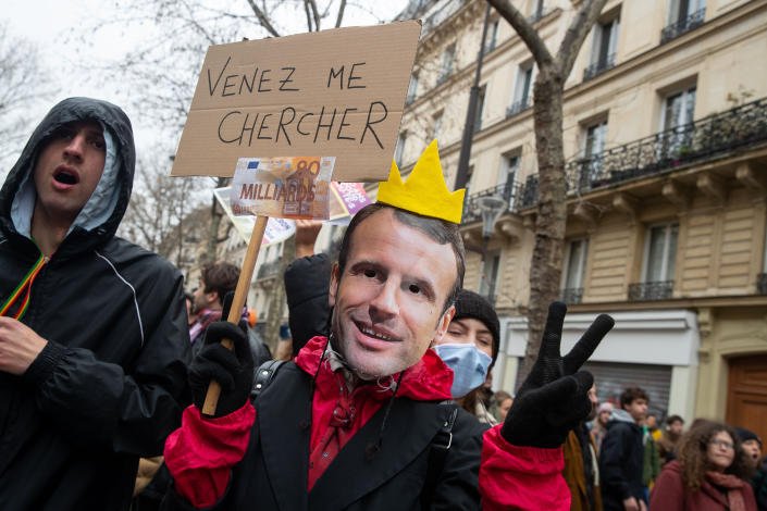Un manifestant portant un masque à l'effigie du président Macron
