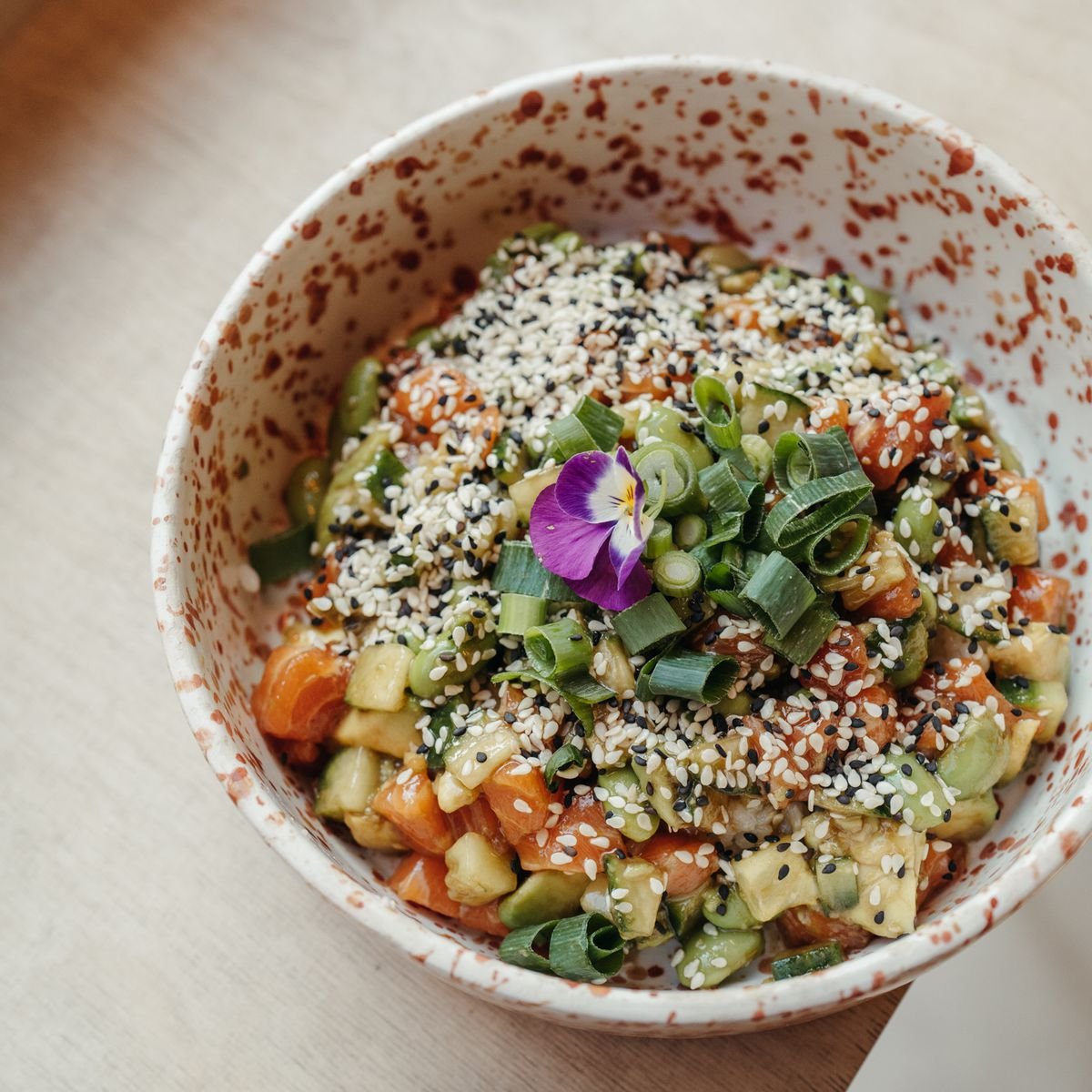 A chopped vegetable salad bowl topped with scallions and sesame seeds. 