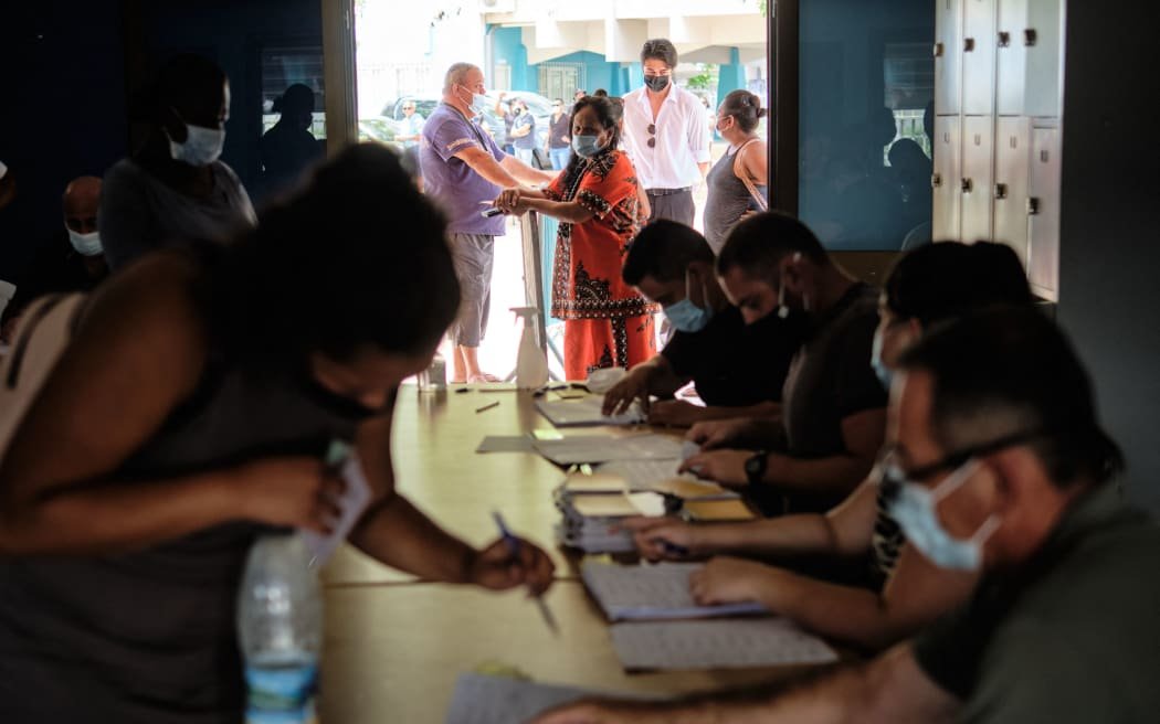 Les gens se préparent à voter pour le référendum sur l'indépendance dans un bureau de vote de l'hôtel de ville de Nouméa, sur le territoire français du Pacifique Sud de la Nouvelle-Calédonie, le 12 décembre 2021.