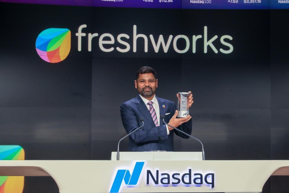 Girish Mathrubootham debout derrière un podium et levant un prix en vue.