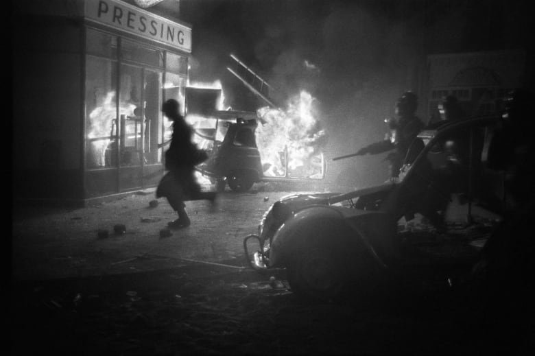Les forces de l'ordre chargent alors qu'une voiture brûle en arrière-plan lors de la nuit des émeutes du 10-11 mai 1968 dans le Quartier Latin à Paris lors des événements de mai-juin 1968.