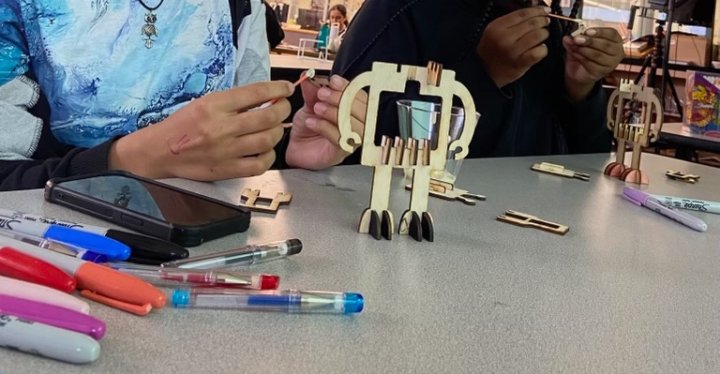 Mains de personnes dans le club de robotique lors de l'assemblage du robot ondulant.