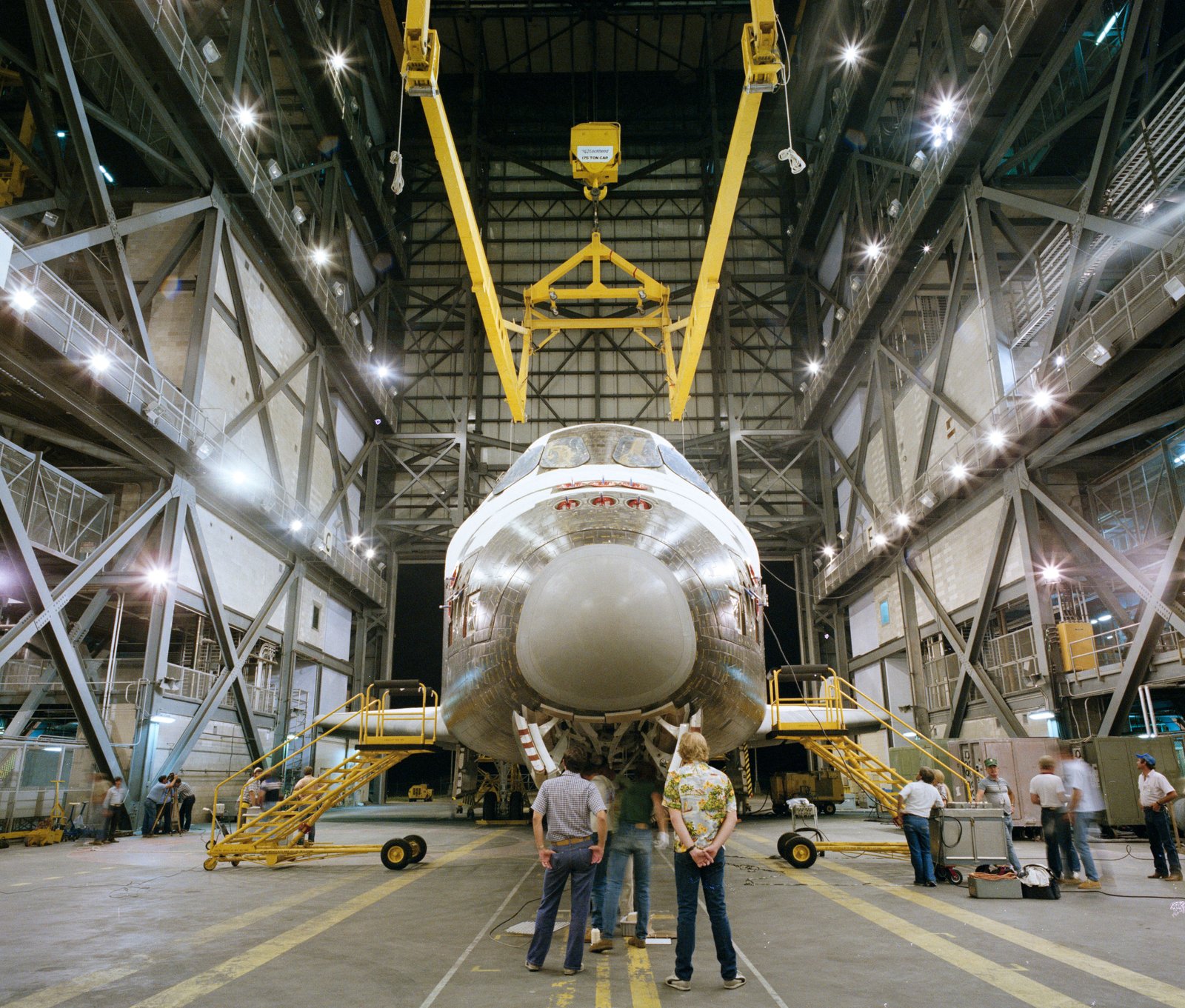 Dans le bâtiment d'assemblage de véhicules (VAB) du centre spatial Kennedy de la NASA en Floride, les travailleurs se préparent à soulever Discovery pour l'accoupler avec son réservoir externe et ses deux propulseurs de fusée à poudre solide.