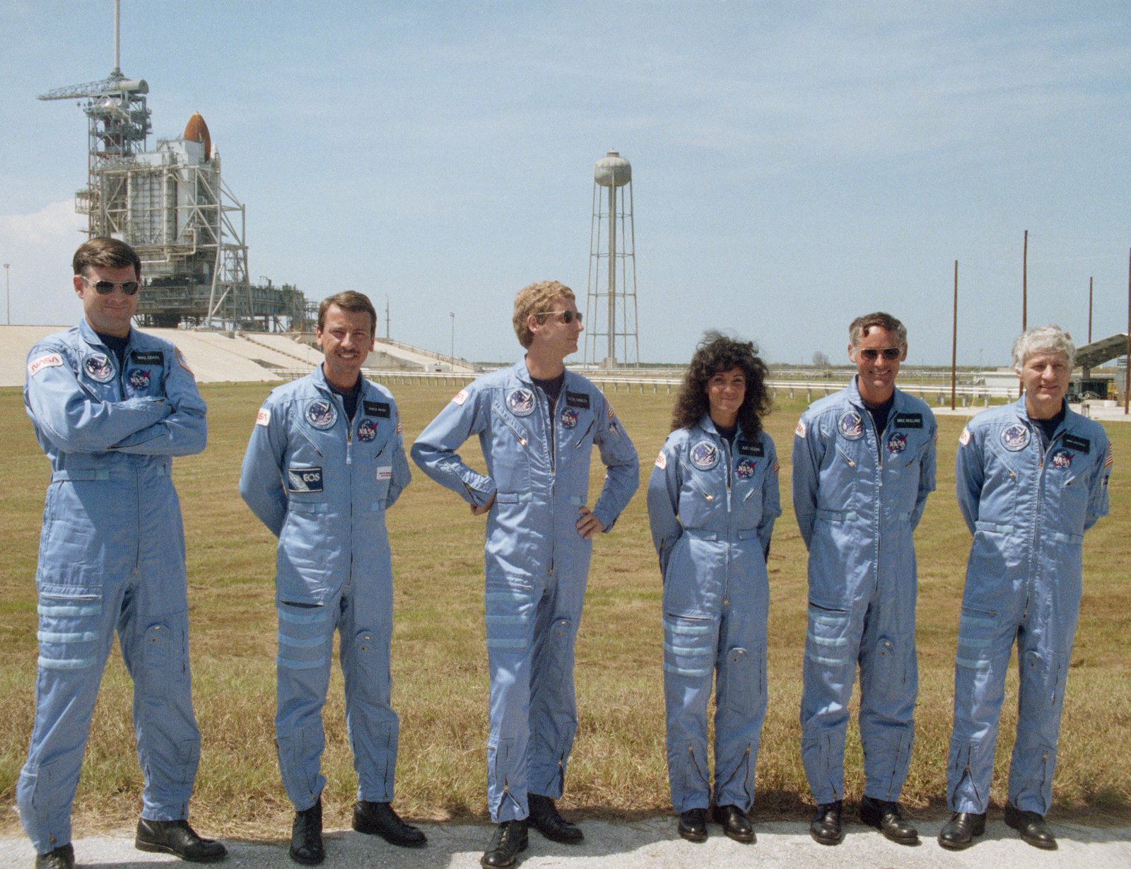 Avec Discovery en toile de fond, les astronautes STS-41D Michael L. Coats, à gauche, Charles D. Walker, Steven A. Hawley, Judith A. Resnik, Richard M. Mike Mullane et Henry W. Hank Hartsfield posent pour les photographes après le test de démonstration du compte à rebours