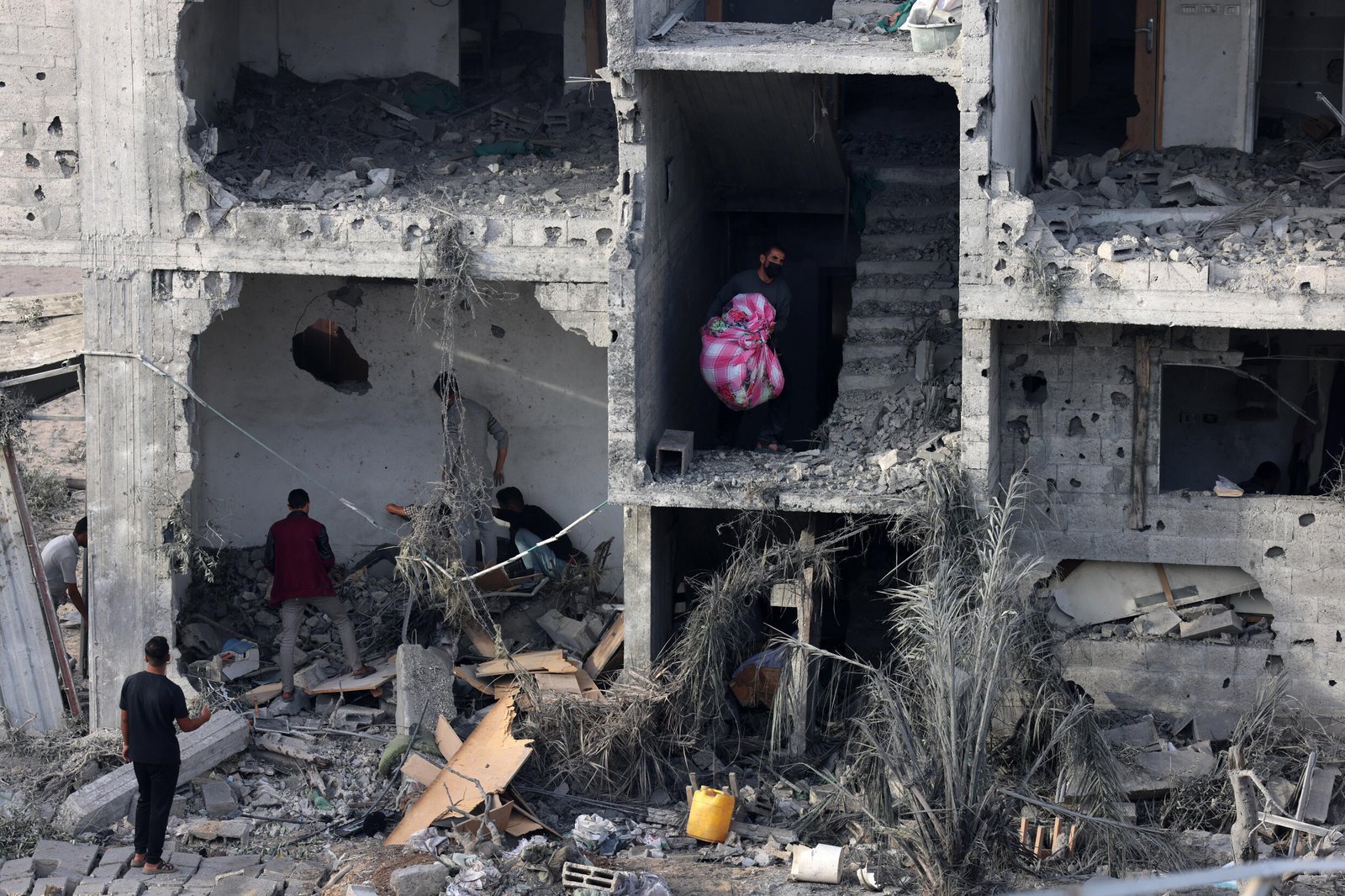 Des gens récupèrent des biens dans un bâtiment endommagé suite à un bombardement dans le sud de la bande de Gaza