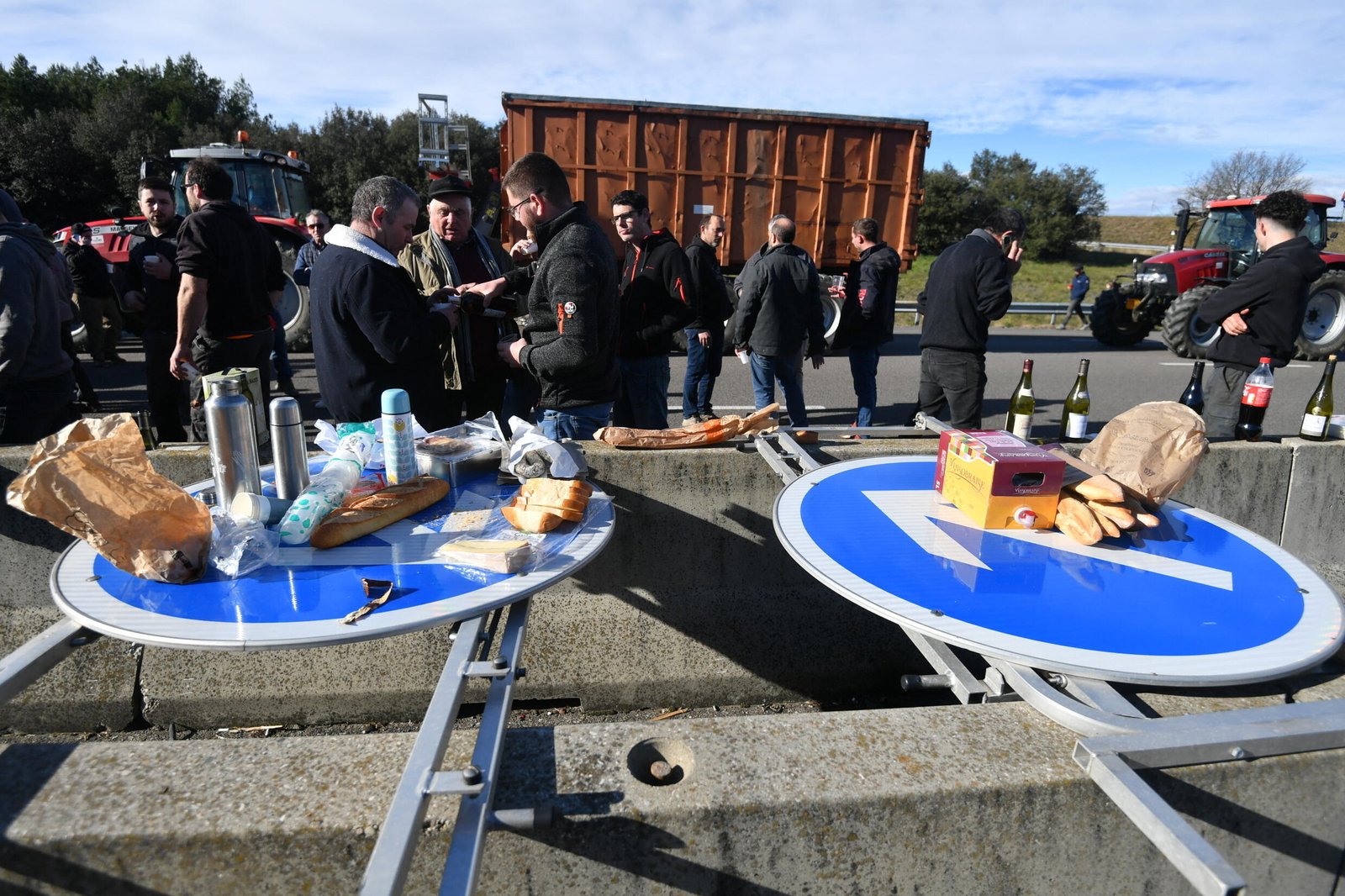 Des agriculteurs interrompent leur manifestation pour déjeuner en utilisant des panneaux routiers comme tables sur l'autoroute A7, dans le sud-est de la France, le 24 janvier 2024.