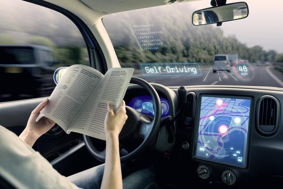 Une personne lit un livre assise dans une voiture autonome.
