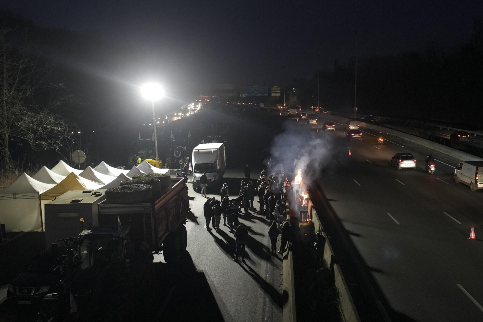Des agriculteurs se rassemblent autour de feux de joie sur une autoroute près d'Argenteuil, au nord de Paris, le 29 janvier 2024.