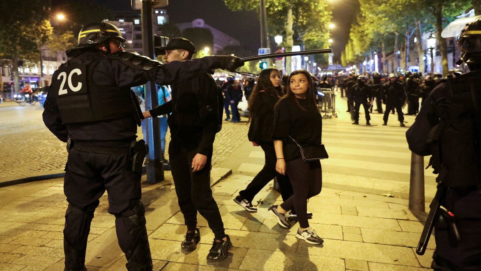Un policier fait des gestes, lors des émeutes suite à la mort de Nahel, un adolescent de 17 ans tué par un policier français à Nanterre lors d'un contrôle routier, sur les Champs Elysées à Paris, France, le 1er juillet 2023.