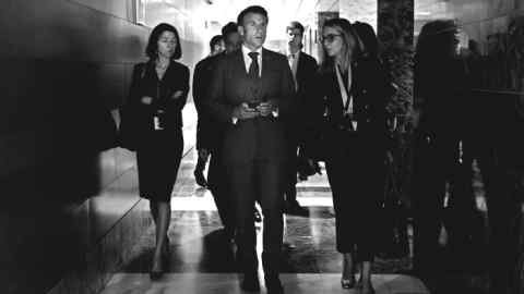 Photo en noir et blanc du président français Emmanuel Macron discutant avec ses conseillers en marchant