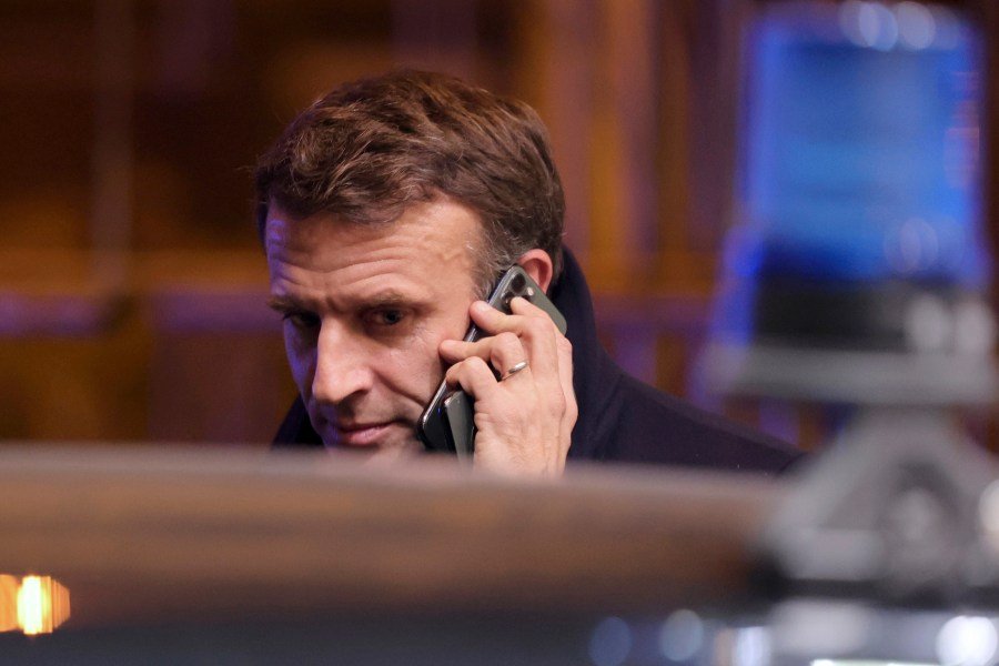 DOSSIER – Le président français Emmanuel Macron s'exprime sur un téléphone portable alors qu'il quitte un sommet européen à Bruxelles, le jeudi 15 décembre 2022. Des responsables du gouvernement français ont accusé lundi la Russie de mener une longue campagne de manipulation en ligne contre les partisans occidentaux de l'Ukraine dans le cela mène au deuxième anniversaire de l’invasion militaire de son voisin par Moscou. (Photo AP/Olivier Matthys, dossier)