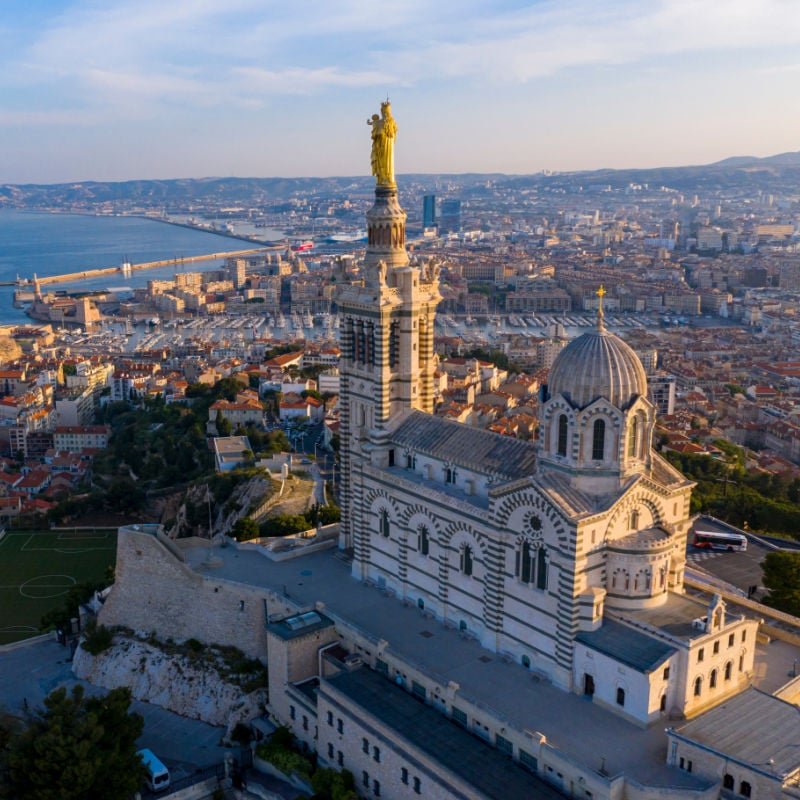 vue aérienne de la basilique et de la ville en contrebas à marseille france au coucher du soleil doré