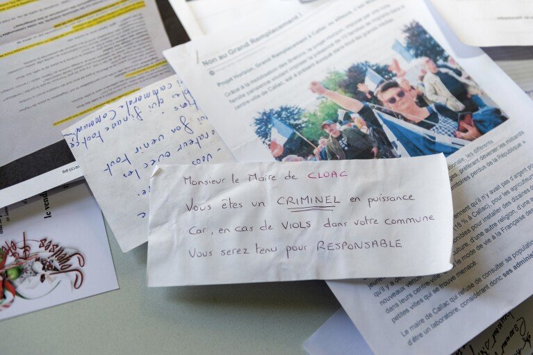 Certaines des lettres de menaces adressées à Jean-Yves Rolland, maire de Callac, sont photographiées le 15 décembre 2023. L'extrême droite a crié victoire en janvier 2023, lorsque Rolland a renoncé à son projet d'héberger sept à dix familles de réfugiés.  (Photo AP/Mathieu Pattier)