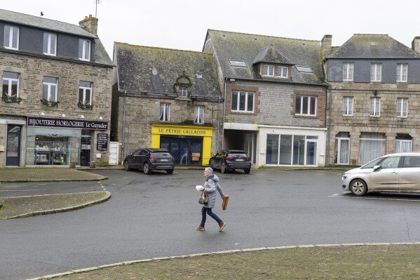 Une femme tient du pain alors qu'elle traverse la rue du village de Callac, le 15 décembre 2023. L'extrême droite a crié victoire en janvier 2023, lorsque le maire Jean-Yves Rolland de Callac a renoncé à son projet d'héberger sept à dix réfugiés. des familles.  (Photo AP/Mathieu Pattier)
