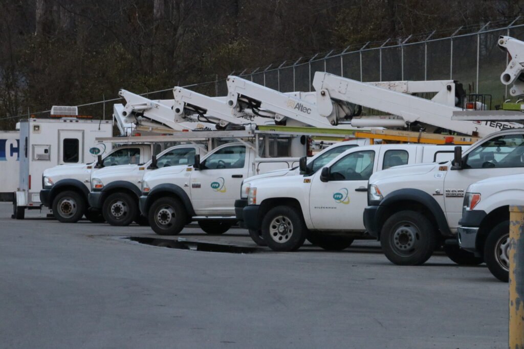 Une ligne de camions-nacelles blancs dotés de bras extensibles permettant aux monteurs de lignes de services publics de travailler dans un parking.