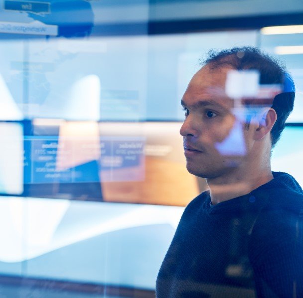 Vue latérale d'un homme, avec des moniteurs en arrière-plan et une superposition de graphisme