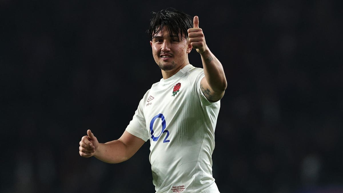 Le joueur de rugby anglais Marcus Smith sourit en célébrant, faisant un geste du pouce levé avec sa main gauche.