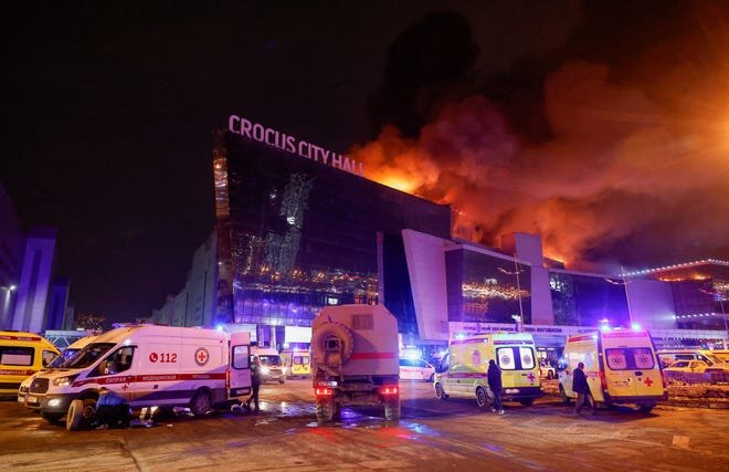 Des véhicules des services d'urgence russes sont garés près de la salle de concert en feu de l'hôtel de ville de Crocus à la suite d'une fusillade signalée, à l'extérieur de Moscou, en Russie, le 22 mars 2024.