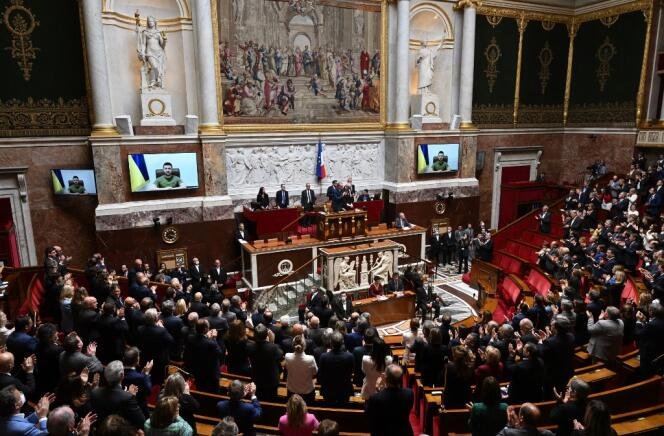 Des députés et sénateurs français lors d'une visioconférence avec le président ukrainien Volodymyr Zelensky (à l'écran), à l'Assemblée nationale à Paris le 23 mars 2022.