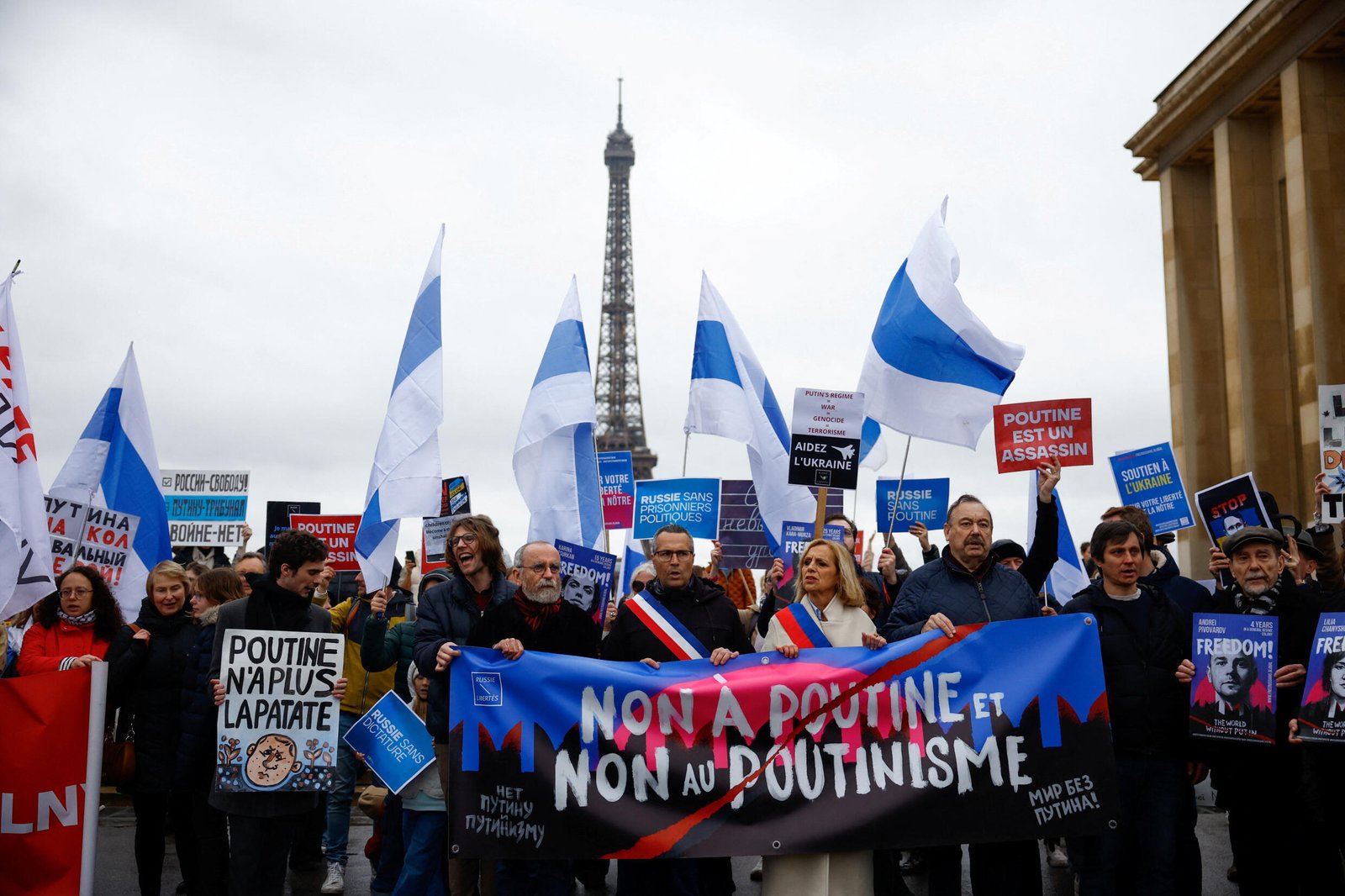 Des gens assistent à une manifestation contre la réélection du président sortant Vladimir Poutine le dernier jour de l'élection présidentielle, place du Trocadéro à Paris, France, le 17 mars 2024. 