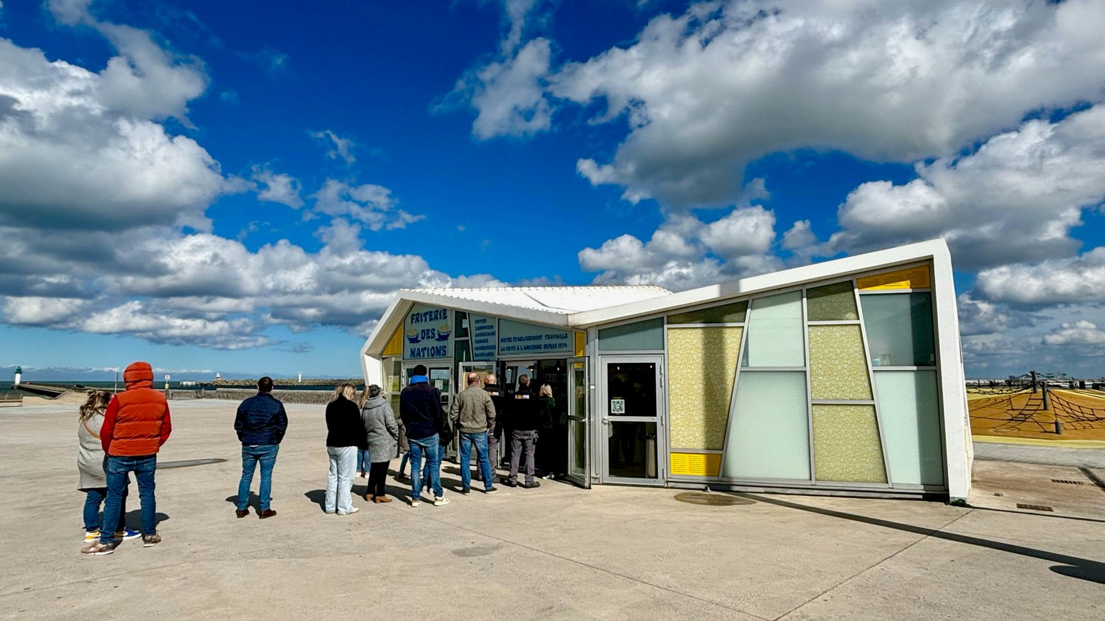 Une file de personnes s’étend devant un kiosque en bord de mer vendant de la nourriture